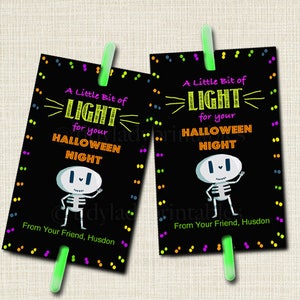 May include: Two black and white printable Halloween party favor tags with a skeleton illustration and the text "A Little Bit of LIGHT for your HALLOWEEN NIGHT" with a glow stick attached to the bottom.