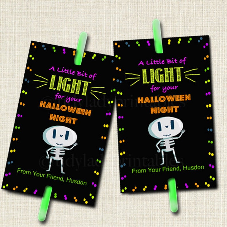 May include: Two black and white printable Halloween party favor tags with a skeleton illustration and the text "A Little Bit of LIGHT for your HALLOWEEN NIGHT" with a glow stick attached to the bottom.