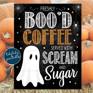 May include: A black chalkboard sign with white text that reads "Freshly Boo'd Coffee Served with Scream and Sugar". A white ghost with two black eyes is in the center of the sign. The sign is surrounded by pumpkins.