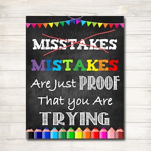 May include: A black chalkboard sign with colorful text that reads "Mistakes are just proof that you are trying". The sign is decorated with colorful pennants and a row of colored pencils at the bottom.