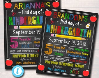May include: Two black chalkboard signs with colorful text announcing the first day of kindergarten for two children. The signs include the children's names, ages, favorite colors, and what they want to be when they grow up. The signs also include the name of the school, the teacher's name, and the year.