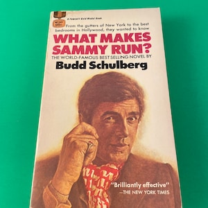 May include: A Fawcett Gold Medal Book paperback cover with a photo of a man wearing a red and white scarf. The book title is "What Makes Sammy Run?" by Budd Schulberg. The book cover also includes a quote from The New York Times: "Brilliantly effective."