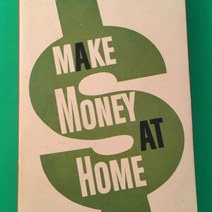May include: A vintage book cover with a green dollar sign graphic and the text "Make Money At Home" by George Anderson. The cover is white with red and black text. The book is priced at 50 cents.