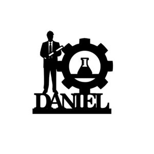 May include: Black silhouette of a person holding a graduation cap and standing next to a gear with a beaker inside. The name "DANIEL" is written below the gear.