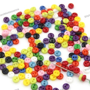 May include: A large assortment of colorful plastic buttons with two holes each. The buttons are in various colors, including red, yellow, blue, green, pink, purple, and white. A needle and thread are also visible in the image.