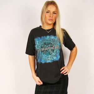 May include: A black t-shirt with a blue and turquoise graphic design and the word "Morphine". The shirt is paired with a green and black plaid mini skirt and black ankle boots.