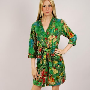May include: A vibrant green robe featuring a colorful, intricate pattern of figures and foliage. This garment has three-quarter length sleeves, a V-neckline, and a matching fabric tie belt at the waist, showcasing visible quilted stitching throughout.