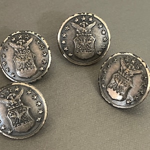 May include: Four silver-toned metal buttons with a star-shaped border and a raised image of the United States Air Force emblem.