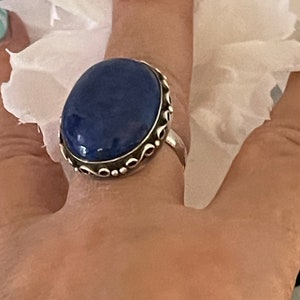 May include: A silver ring with a large oval blue gemstone set in a decorative silver band.