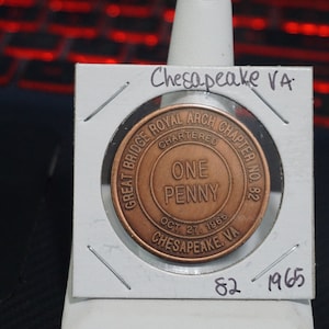 May include: A copper-colored token with the inscription "Great Bridge Royal Arch Chapter No. 82 Chartered Oct 27, 1965 Chesapeake VA One Penny" and the year "1965" on the back.