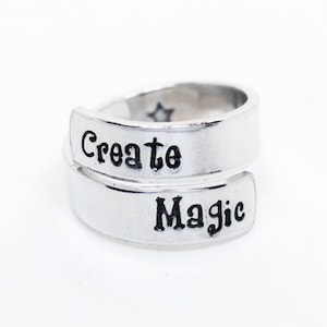 May include: A silver ring with the words "Create Magic" engraved on it.