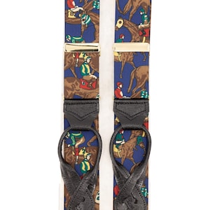 Può includere: Bretelle con sfondo blu e motivo ripetuto di cavalli marroni e fantini con colorate sete da equitazione. Le bretelle hanno chiusure metalliche color oro e passanti in pelle nera.
