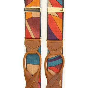 Può includere: Bretelle fantasia con un design geometrico colorato nei toni del rosso, arancione, blu e viola. Le bretelle hanno chiusure in metallo color oro e dettagli in pelle marrone. Progettate per essere indossate con i pantaloni.
