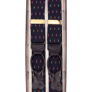 Può includere: Bretelle blu navy con un motivo a rombi ripetuto in rosso, arancione, verde e viola. Le bretelle hanno chiusure in metallo color oro e estremità in pelle nera. Le bretelle sono esposte in una scatola marrone.
