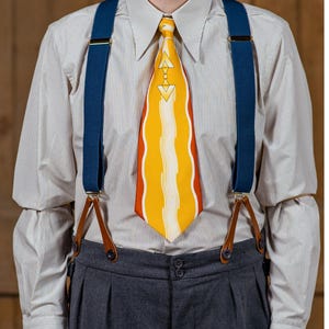 May include: A man wearing a white striped dress shirt with a yellow and orange patterned tie and blue suspenders with brown leather accents. The suspenders are attached to gray trousers.