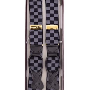 May include: A pair of checkered suspenders in a box. The suspenders have a black and gray checkered pattern, gold-colored clasps, and black leather attachments. The box is a dark burgundy color.