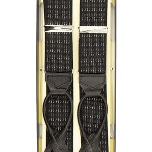 May include: Black suspenders with a white dotted pattern, presented in a box. The suspenders feature silver-coloured metal clasps and black leather loops. The box has a cream-coloured interior.