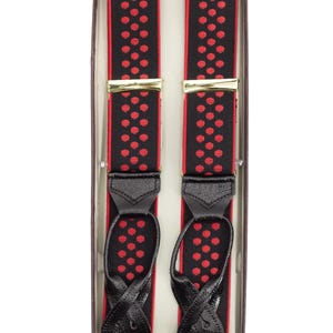 May include: Black suspenders with red polka dots, presented in a box. The suspenders have gold-colored clasps and black leather attachments. The design features a repeating pattern of red dots on a black background.
