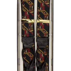 May include: Black suspenders with a geometric pattern in red, gold, and white, presented in a box. The suspenders have gold-coloured metal clasps and black leather attachments. A classic accessory.