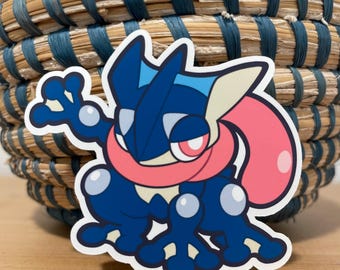 May include: A blue and pink cartoon frog sticker with a white outline. The frog is waving with its right hand and has a large, pink tongue.