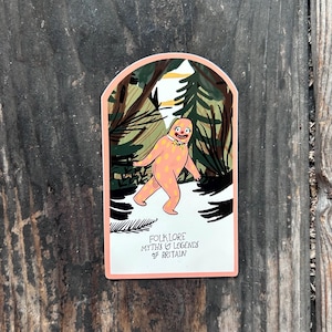 May include: An arched sticker featuring a peach-coloured creature with yellow spots, wearing a white collar and yellow bow tie, walking through a dark forest. The text at the bottom reads: FOLKLORE MYTHS & LEGENDS OF BRITAIN in black lettering.