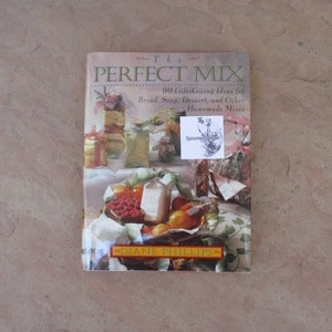 May include: A cookbook titled "The Perfect Mix" by Diane Phillips, featuring a colorful cover with images of homemade food mixes. The book's title and author's name are prominently displayed, with text indicating gift-giving ideas for various recipes.