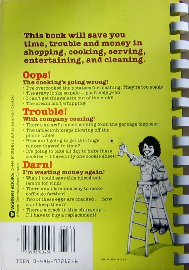 May include: A vintage cookbook cover with a bright yellow background and white spiral binding. The cover features text about saving time and money in the kitchen, along with humorous cooking mishaps and a cartoon illustration of a person on a step stool.