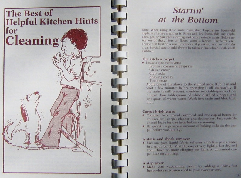 May include: An open book with a spiral binding, featuring a cartoon illustration of a boy and a dog. The text reads "The Best of Helpful Kitchen Hints for Cleaning" and cleaning tips.