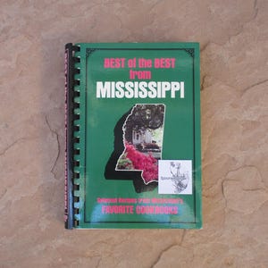 May include: A spiral-bound cookbook titled "BEST of the BEST from MISSISSIPPI" with a green cover. The cover features the state outline with a photo of a house and flowers. Text includes "Selected Recipes From Mississippi's FAVORITE COOKBOOKS."