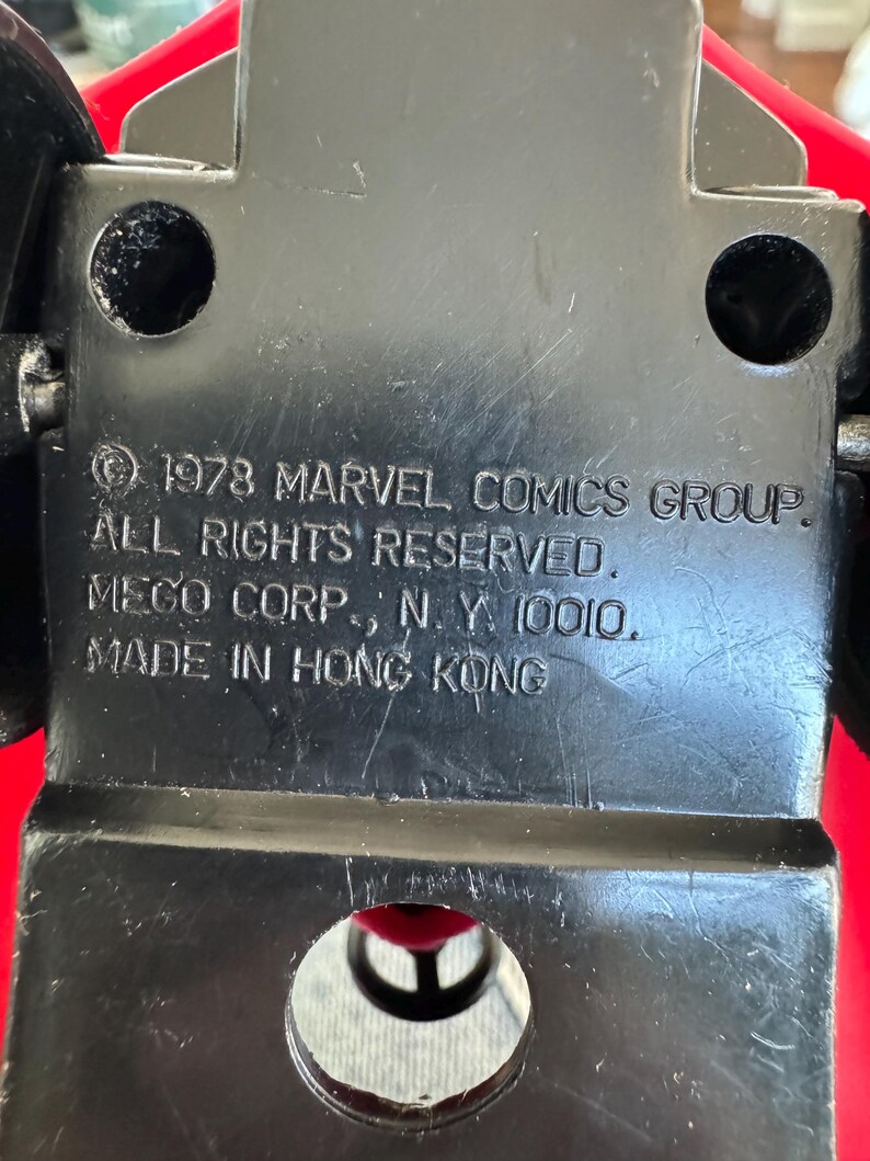 Pu&ograve; includere: Macchina giocattolo in plastica nera con carrozzeria rossa e ruote nere. La parte inferiore dell'auto ha il testo "1978 MARVEL COMICS GROUP. ALL RIGHTS RESERVED. MEGO CORP., N. Y. 10010. MADE IN HONG KONG".