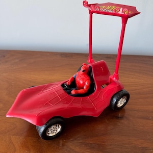 Pu&ograve; includere: Macchina giocattolo rossa con una figura di Spider-Man sul sedile del conducente. La macchina ha un design a ragnatela e una cappottina con le parole "Amazing Spider-Man" stampate su di essa.