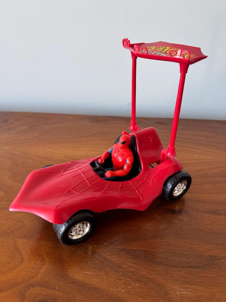 Pu&ograve; includere: Macchina giocattolo rossa con una figura di Spider-Man sul sedile del conducente. La macchina ha un design a ragnatela e una cappottina con le parole "Amazing Spider-Man" stampate su di essa.