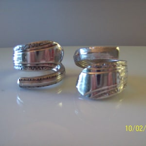 May include: Two silver rings made from twisted silverware. The rings have a decorative pattern.