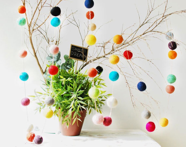 Puede incluir: Una guirnalda de bolas de fieltro de colores cuelga de una rama. Las bolas son de varios colores, incluyendo rojo, naranja, amarillo, verde, azul, morado y blanco. La guirnalda est&aacute; decorada con las palabras "Sweet Dreams".
