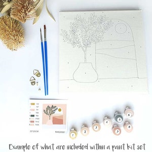 Puede incluir: Un kit de pintura por n&uacute;meros con un lienzo preimpreso que presenta un jarr&oacute;n con una planta, una luna y un paisaje. El kit incluye ocho botes de pintura, dos pinceles y dos ganchos para colgar. El lienzo mide 20x20cm.