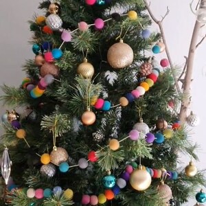 Puede incluir: Un &aacute;rbol de Navidad decorado con una guirnalda de bolas de fieltro de colores. La guirnalda presenta una variedad de colores, incluyendo rojo, azul, verde, amarillo y rosa. El &aacute;rbol tambi&eacute;n est&aacute; decorado con adornos dorados y plateados.