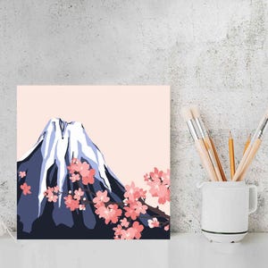 Puede incluir: Una ilustraci&oacute;n digital del Monte Fuji con flores de cerezo rosas en primer plano. La monta&ntilde;a se representa en un esquema de color azul y blanco, con un cielo rosa en el fondo.