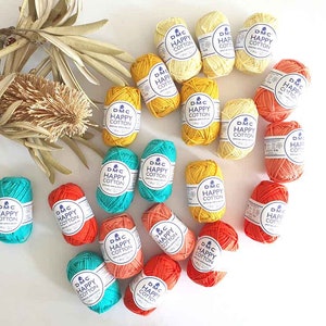 Pu&ograve; includere: Una collezione di gomitoli di lana colorati in tonalit&agrave; di arancione, giallo e turchese. Ogni gomitolo ha un'etichetta che recita "DMC Happy Cotton".