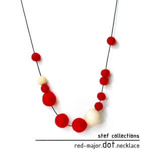 May include: A red and white felt ball necklace. The necklace is made of red and white felt balls strung on a black cord. The necklace is called "red-major.dot.necklace" and is from "stef collections".