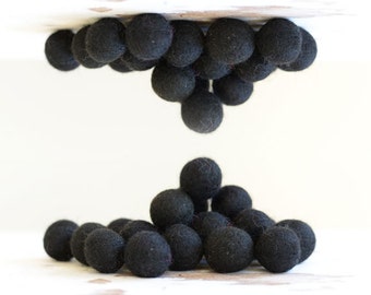 May include: A group of black felt balls arranged in a pyramid shape. The balls are soft and fluffy, and they would be perfect for a craft project or decoration.