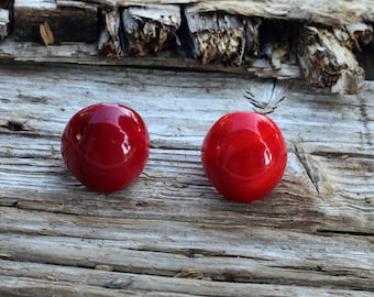 May include: Two shiny red round buttons on a weathered wooden surface.