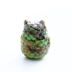 May include: A small, green, and brown ceramic owl figurine with a textured surface.