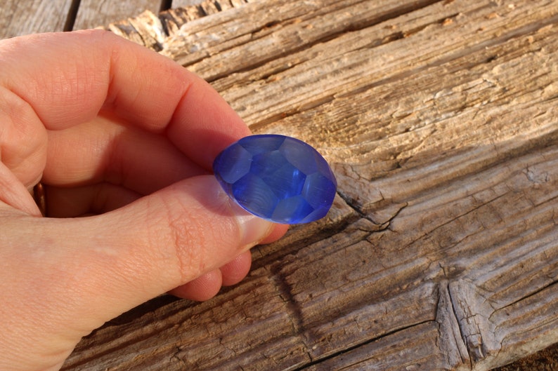 May include: A blue faceted glass bead with a smooth, polished surface.