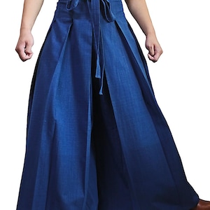 May include: A pair of wide-legged pants with a tie at the waist. The pants are a dark blue color and have pleats down the front.