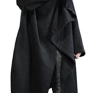 May include: A long, black coat with an oversized hood and asymmetrical design. The coat is made of a soft, flowing fabric and features a button closure at the neck. The model is wearing blue jeans.