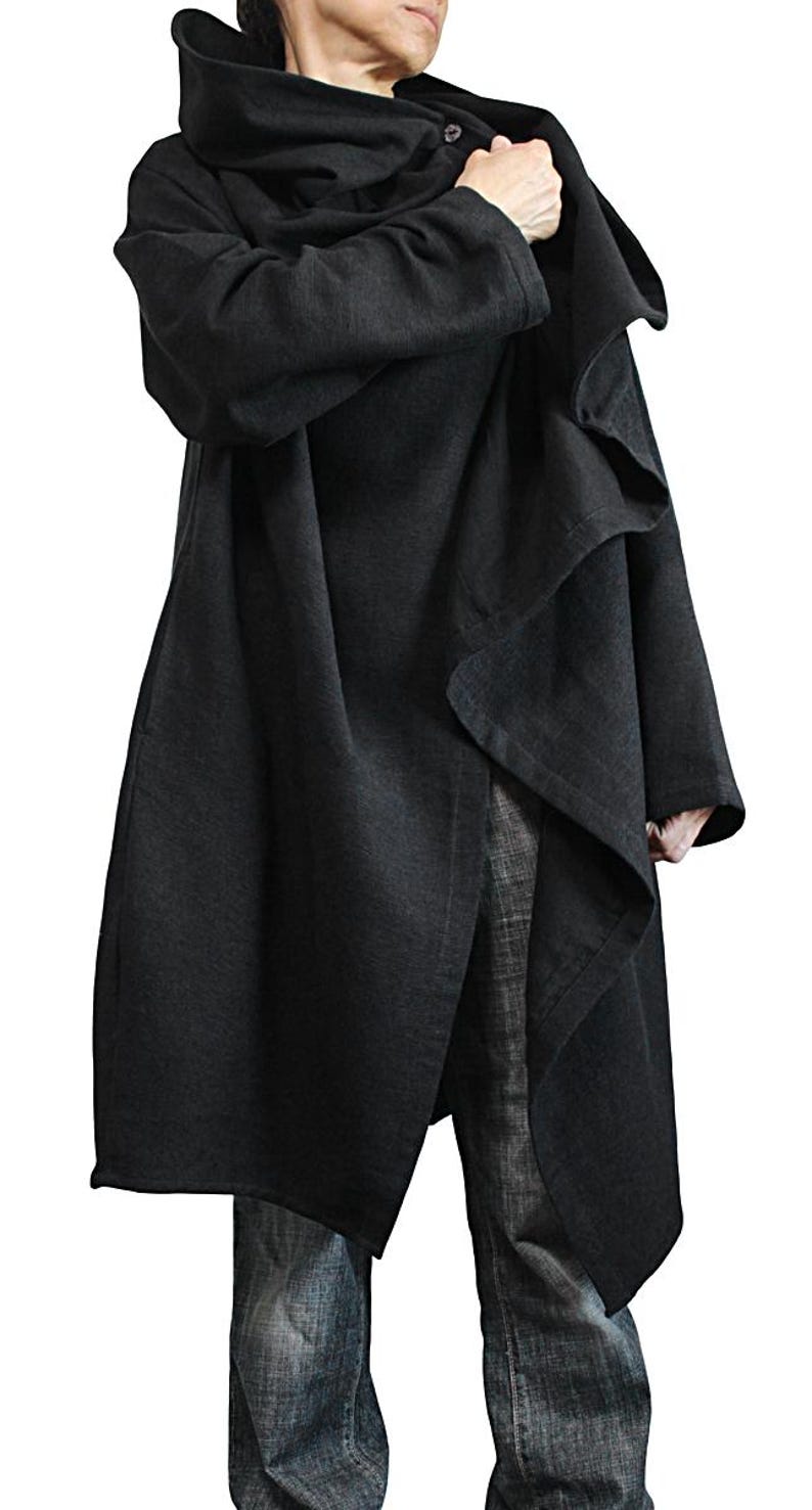May include: A long, black coat with an oversized hood and asymmetrical design. The coat is made of a soft, flowing fabric and features a button closure at the neck. The model is wearing blue jeans.