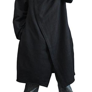 May include: A long, black coat with a hood. The coat has a wrap-style design and is worn with blue jeans. The coat appears to be made of a heavy fabric, suitable for cooler weather. The overall style is minimalist and modern.
