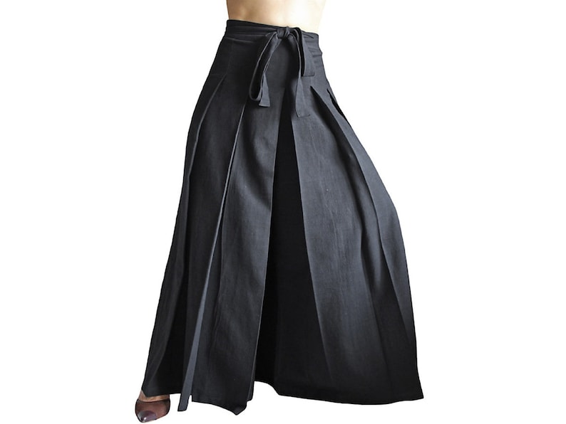 May include: A black, floor-length skirt with a wide waistband and a tie at the front. The skirt has pleats throughout and a split in the front.