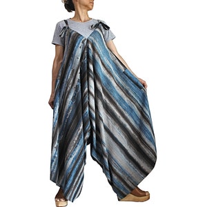 Könnte beinhalten: Ein blauer und grauer gestreifter Jumpsuit mit lockerer Passform und V-Ausschnitt. Der Jumpsuit hat einen Knoten an den Schultern und Taschen an den Seiten.