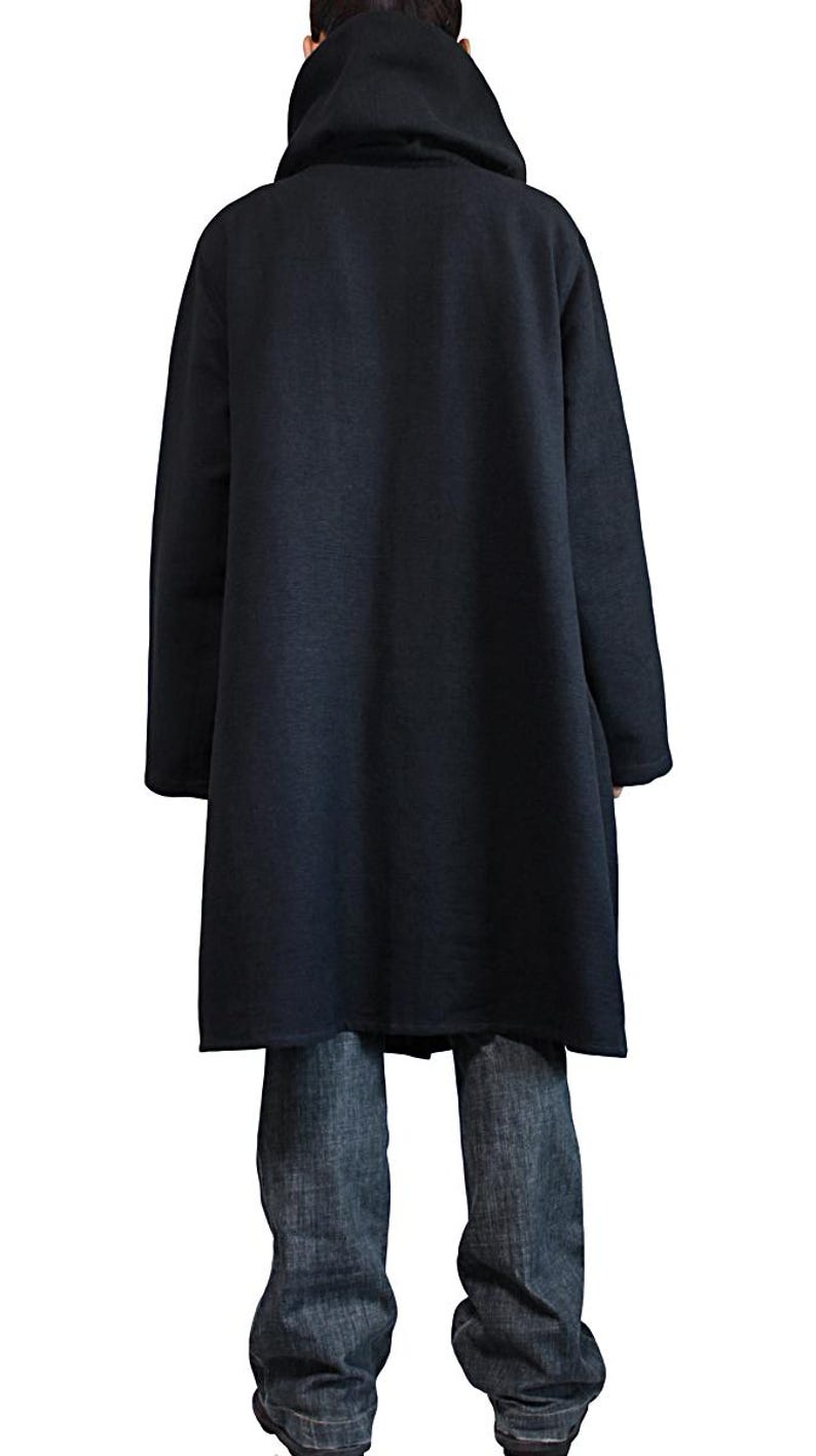 May include: A long, black hooded coat with long sleeves. The coat is made of a soft, dark fabric and reaches to the mid-calf. The person is wearing blue jeans. The background is white.